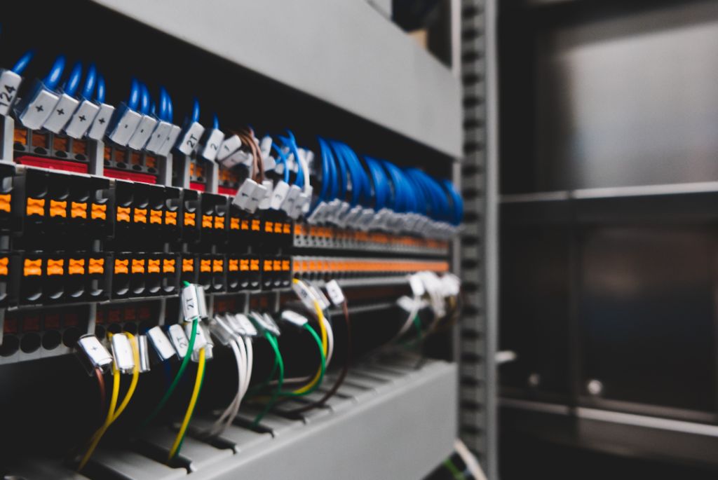 Close-up of electrical panel with labeled terminal blocks, blue cables, and color-coded wiring