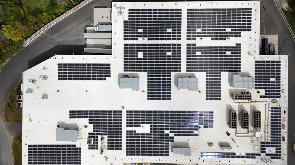 Aerial view of commercial rooftop solar panel installation on large industrial building