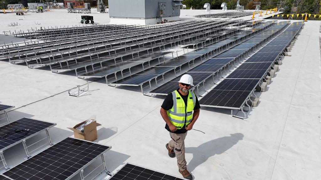 Electrician walking through commercial rooftop solar panel installation
