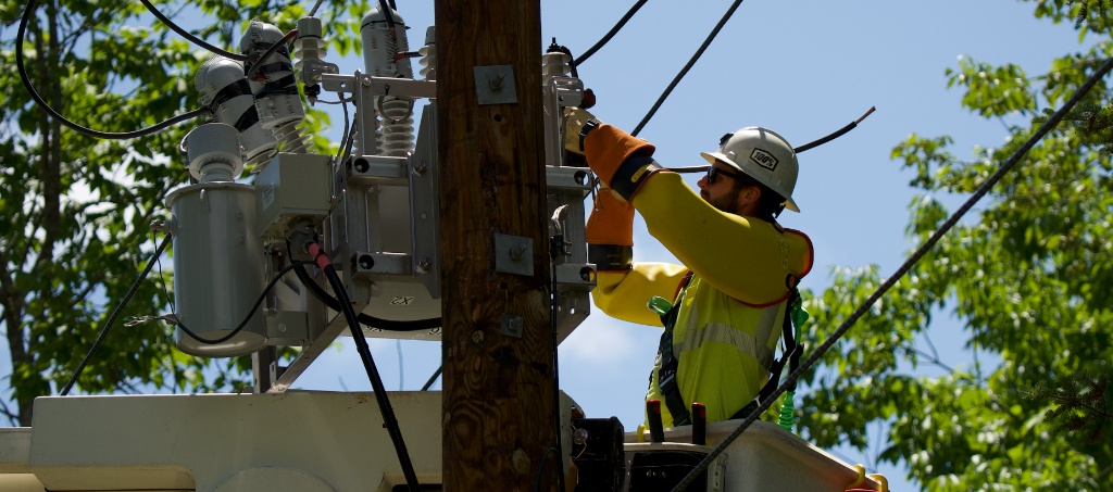 Utility lineman performing power pole maintenance and transformer work from a bucket truck
